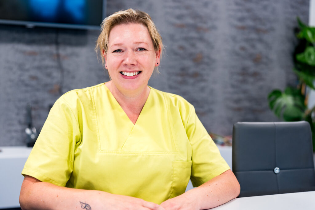 Mitarbeiterin von Janine's Pflegeteam am Schreibtisch im Buero